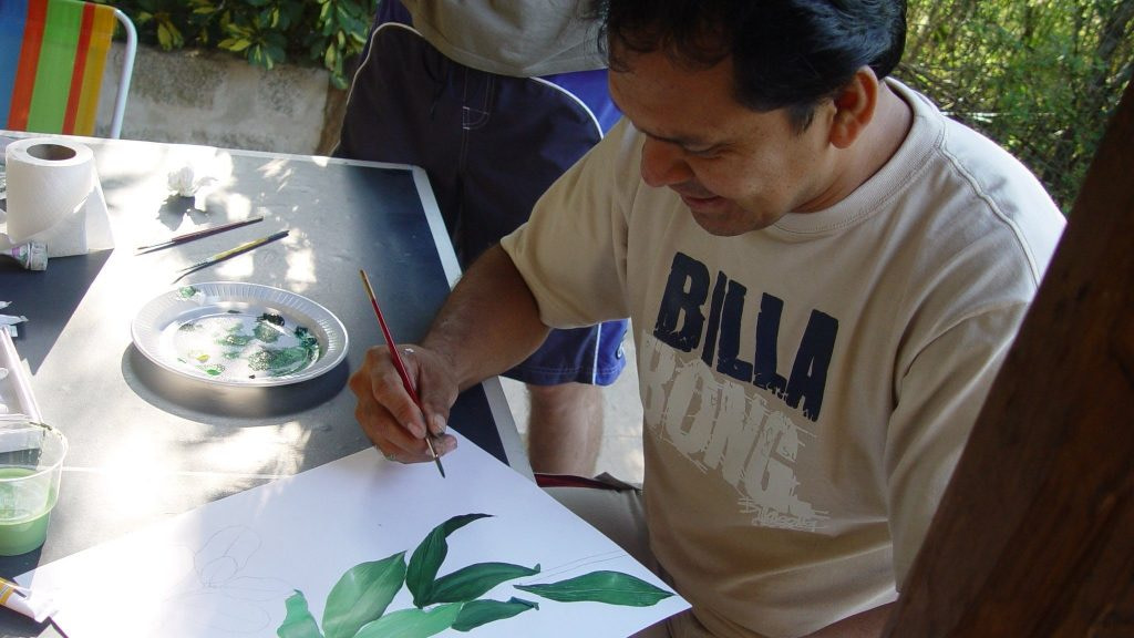 A man painting a leaf on a piece of paper.