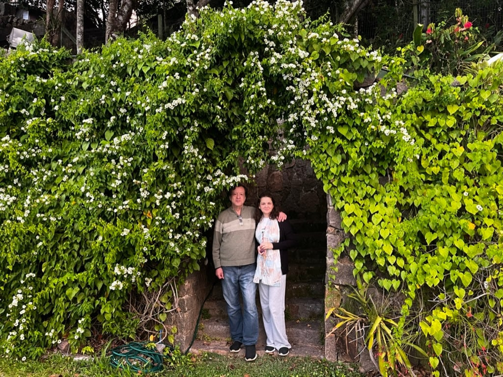 A man and woman standing in front of a stone archway.