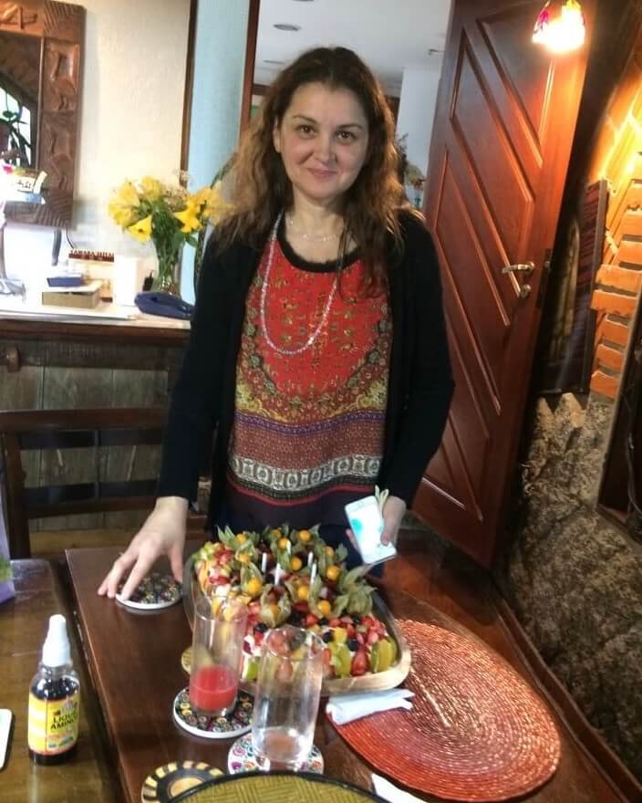 M.A. Adriana Luna standing in front of a table with fruit on it.